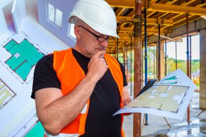 image d'un architecte sur un chantier avec un plan dans les mains
